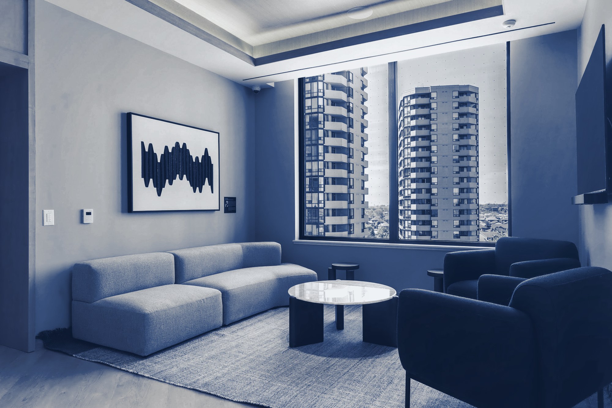 Modern apartment lounge with sofa, armchairs, abstract art and a city tower view, tinted navy